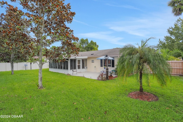 back of property with a patio, a sunroom, and a lawn