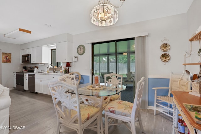 dining room featuring light wood-type flooring, a chandelier, and sink