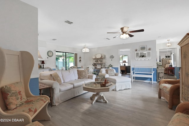 living room featuring a large fireplace, hardwood / wood-style floors, and ceiling fan with notable chandelier