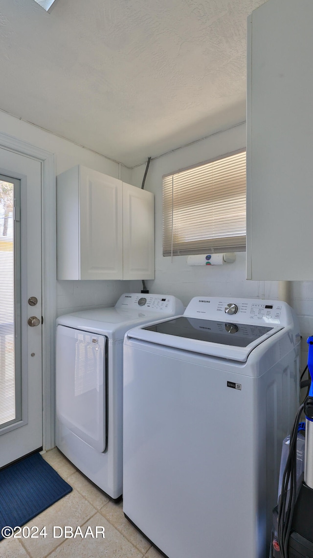 laundry room featuring cabinets, light tile patterned floors, and washer and clothes dryer