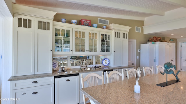 kitchen featuring a kitchen bar, white cabinetry, vaulted ceiling with beams, and light stone counters