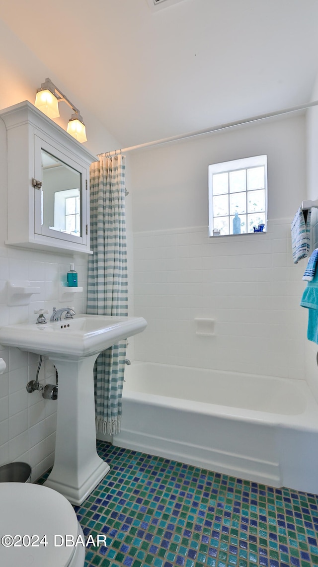 bathroom with tile walls, toilet, and shower / bathtub combination with curtain