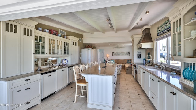 kitchen with beamed ceiling, sink, a breakfast bar, custom exhaust hood, and a center island