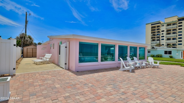 rear view of house with a patio and a storage unit