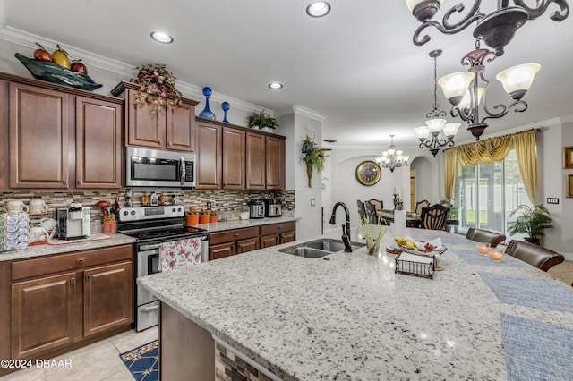 kitchen with ornamental molding, appliances with stainless steel finishes, sink, and light stone countertops