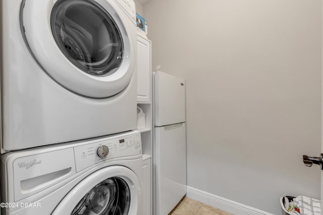 laundry room with stacked washer and dryer, cabinets, and light tile patterned floors