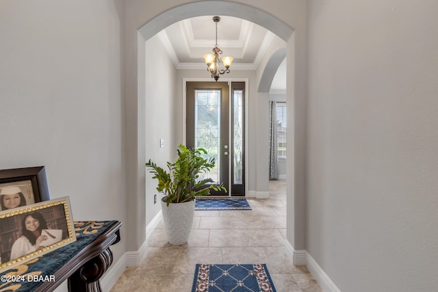 tiled entryway with a chandelier, a tray ceiling, and crown molding