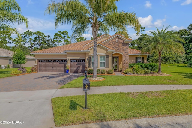 mediterranean / spanish home featuring a garage and a front lawn