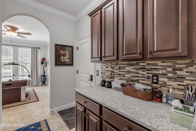 kitchen with light stone countertops, dark brown cabinets, ornamental molding, and tasteful backsplash