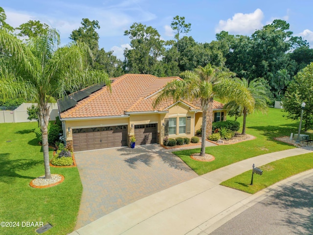 mediterranean / spanish-style house featuring a front yard and a garage