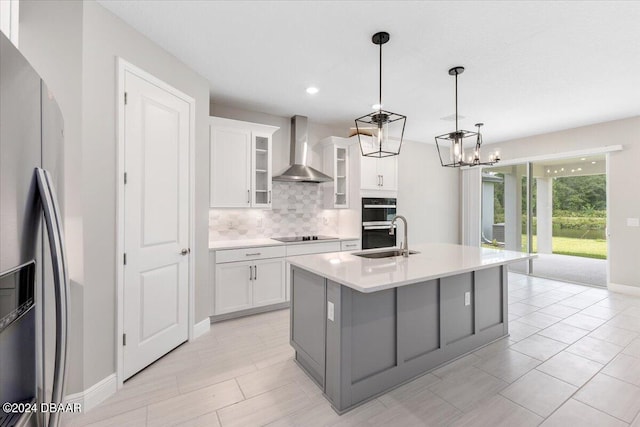 kitchen featuring sink, wall chimney range hood, a center island with sink, white cabinets, and black appliances