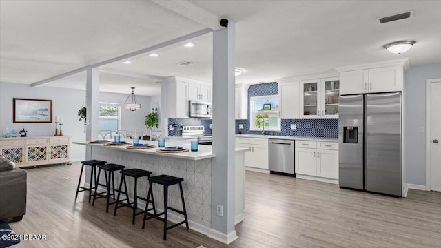 kitchen featuring white cabinetry, plenty of natural light, stainless steel appliances, and light hardwood / wood-style flooring