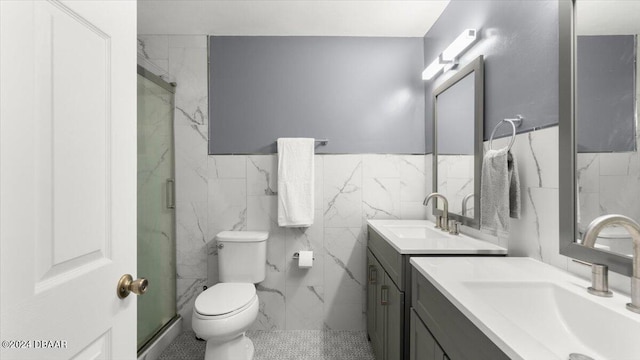 bathroom featuring vanity, a shower with door, tile patterned flooring, toilet, and tile walls