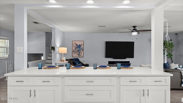 kitchen with ceiling fan, white cabinets, and wood-type flooring