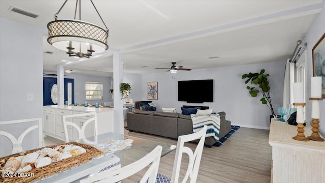 dining room with light hardwood / wood-style flooring and ceiling fan with notable chandelier