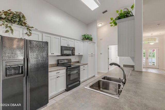 2853 Turnbull Estates Dr, New Smyrna Beach, FL 32168 - kitchen with sink, black appliances, high vaulted ceiling, white cabinetry, and light tile patterned flooring