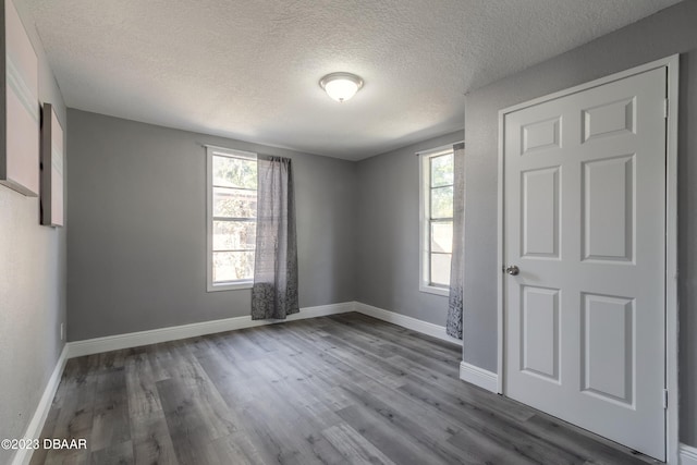 empty room with hardwood / wood-style floors and a textured ceiling