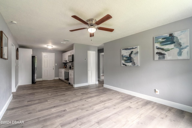 unfurnished living room with a textured ceiling, light hardwood / wood-style flooring, and ceiling fan