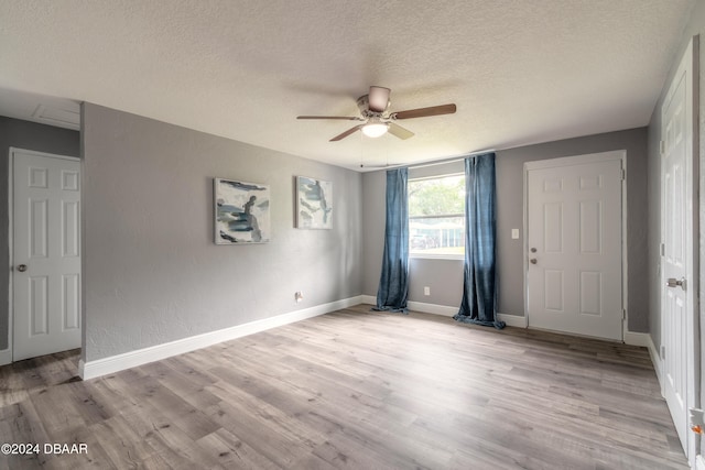 empty room featuring ceiling fan, a textured ceiling, and light hardwood / wood-style floors