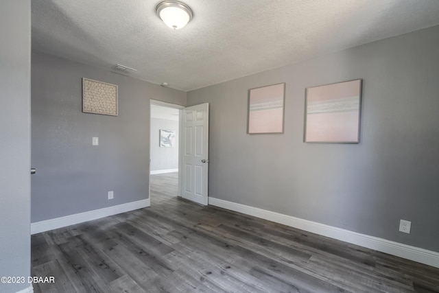 unfurnished room featuring a textured ceiling and dark hardwood / wood-style floors