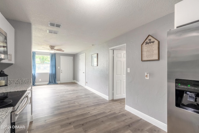 kitchen with light hardwood / wood-style floors, ceiling fan, a textured ceiling, and appliances with stainless steel finishes