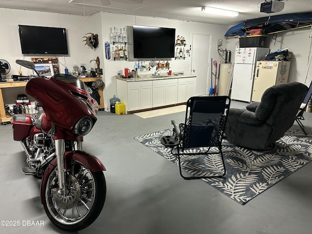 interior space with white fridge, sink, a workshop area, and a textured ceiling