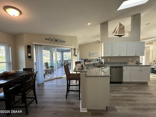 kitchen featuring sink, dishwasher, a kitchen breakfast bar, white cabinets, and kitchen peninsula