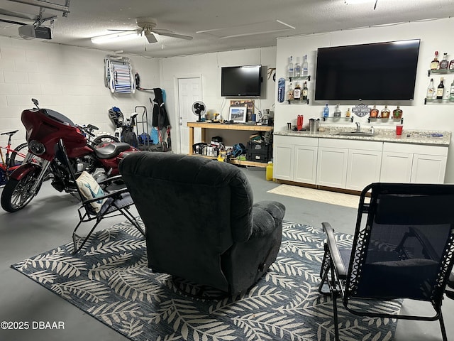 living room featuring ceiling fan, wet bar, and concrete floors