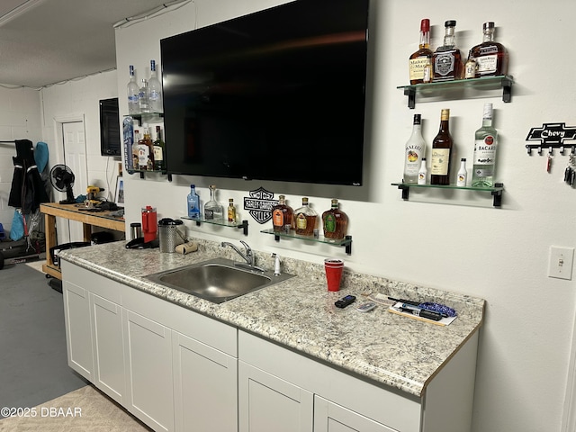 kitchen with sink, light stone countertops, and white cabinets