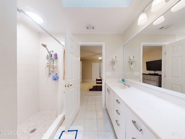 bathroom with vanity, tile patterned flooring, and a tile shower