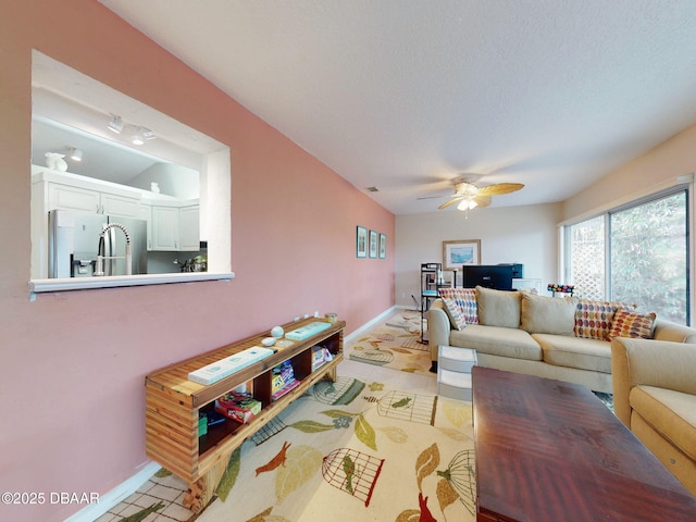 living room with ceiling fan and a textured ceiling