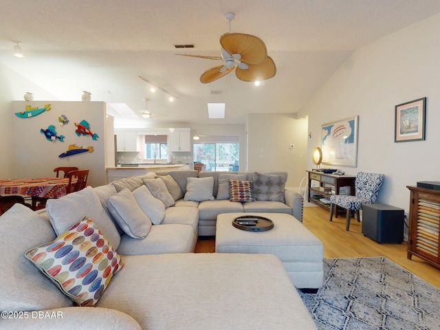 living room featuring sink, vaulted ceiling, light hardwood / wood-style floors, and ceiling fan