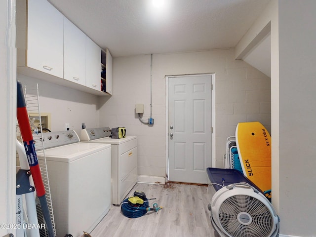 washroom featuring cabinets, separate washer and dryer, a textured ceiling, and light hardwood / wood-style flooring