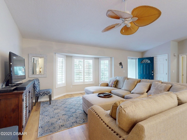 living room featuring ceiling fan, lofted ceiling, and light hardwood / wood-style floors