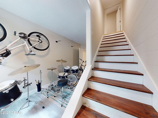 stairs with wood-type flooring and a textured ceiling