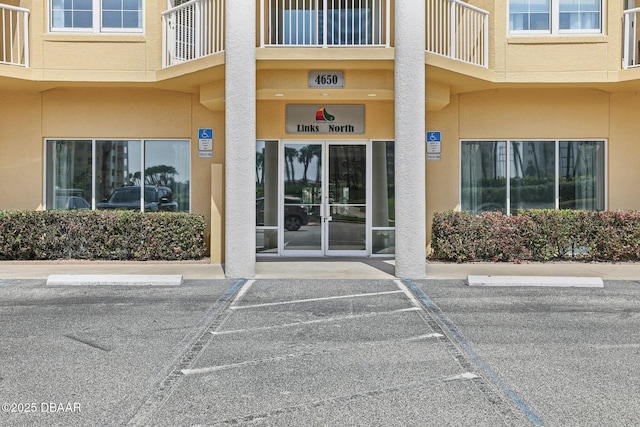 4650 Links Village Dr Unit B103, Ponce Inlet, FL 32127 - view of exterior entry featuring uncovered parking, stucco siding, and a balcony