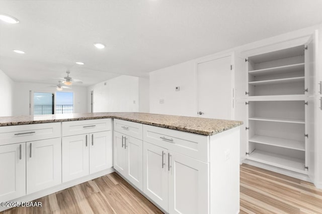 3807 S Atlantic Ave Unit 2020, Daytona Beach, FL 32118 - kitchen featuring light wood-style floors, a ceiling fan, light stone countertops, white cabinets, and open shelves
