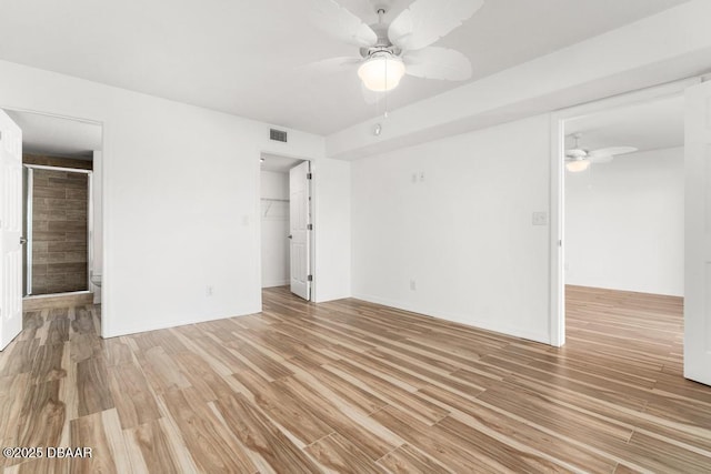 3807 S Atlantic Ave Unit 2020, Daytona Beach, FL 32118 - unfurnished bedroom featuring a walk in closet, light wood-style floors, a closet, and a ceiling fan