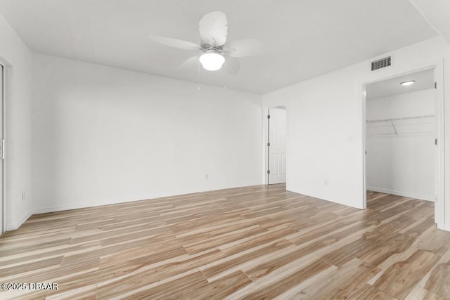 3807 S Atlantic Ave Unit 2020, Daytona Beach, FL 32118 - unfurnished bedroom with light wood-style flooring, ceiling fan, a closet, and a walk in closet