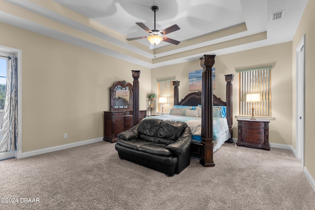 carpeted bedroom featuring ceiling fan and a raised ceiling