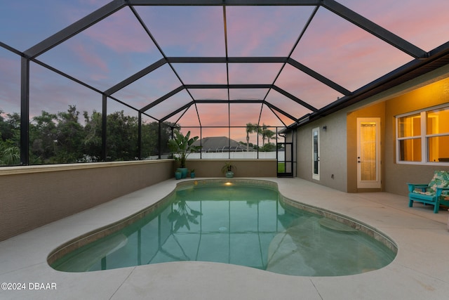 pool at dusk featuring a patio and a lanai