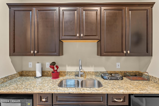 kitchen featuring light stone countertops, dark brown cabinets, dishwasher, and sink