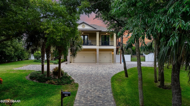 view of front of property featuring a yard, a balcony, and a garage