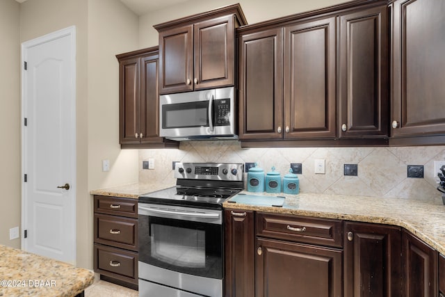 kitchen featuring decorative backsplash, dark brown cabinets, stainless steel appliances, and light stone counters