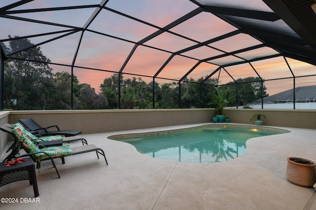 pool at dusk with a lanai and a patio