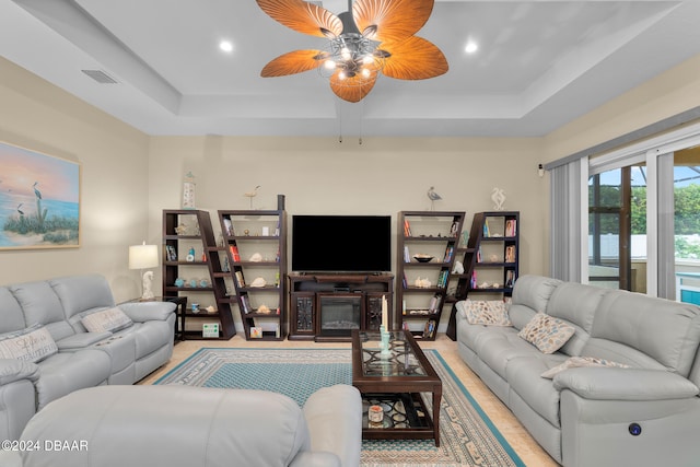 living room with a tray ceiling and ceiling fan