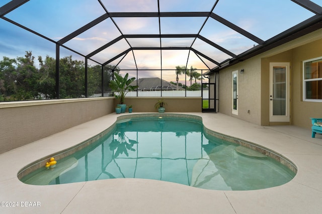 pool at dusk featuring a lanai and a patio