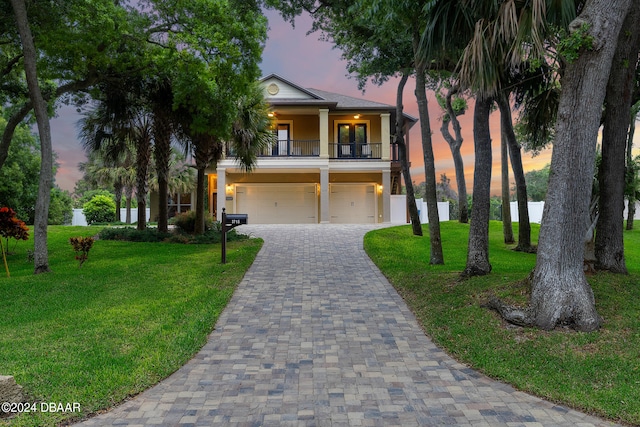 view of front of property featuring a yard, a balcony, and a garage