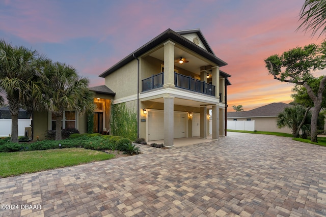 view of front facade with a balcony, a garage, and ceiling fan