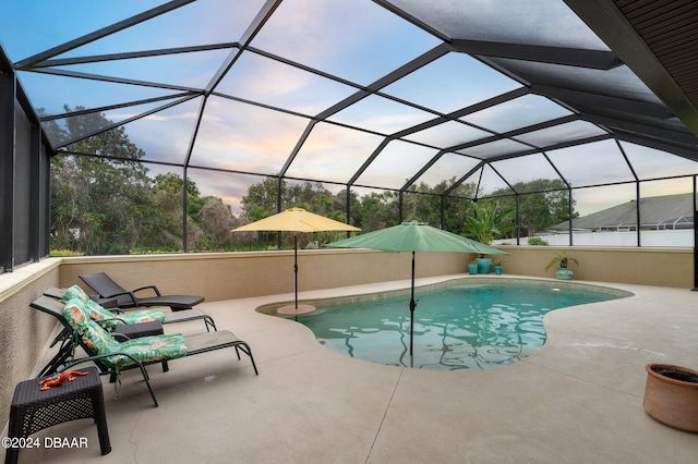 pool at dusk with a lanai and a patio